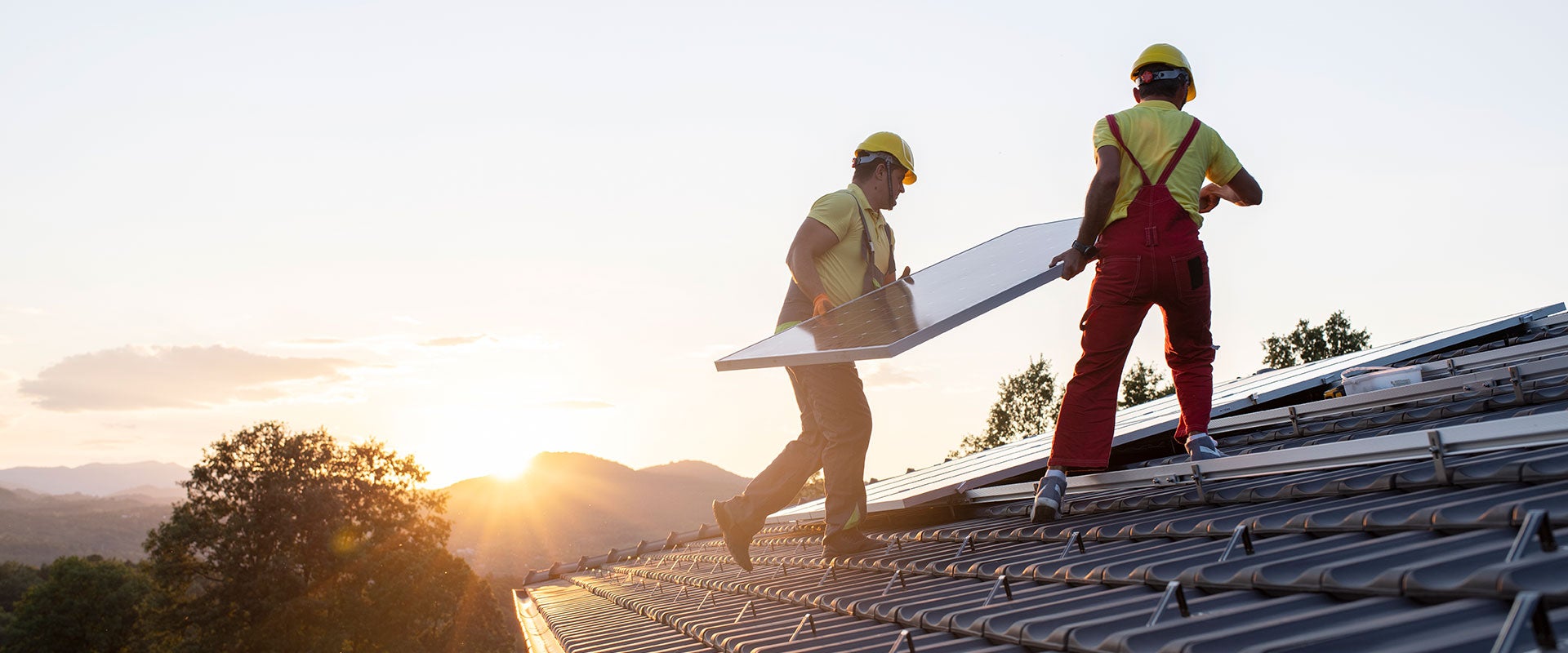 construction workers putting solar panels on roof